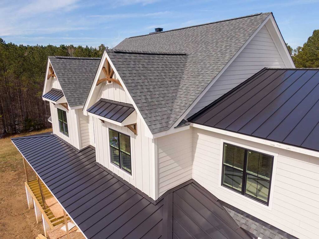 Dark roof shingles with green mildew patches and a person inspecting the area from the ground.