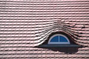 Inspector examining roof shingles and flashing beside a ladder while documenting visible wear.